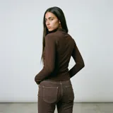 Polera de manga larga en color negro, con cuello alto y costuras decorativas visibles en el frente que realzan la silueta.