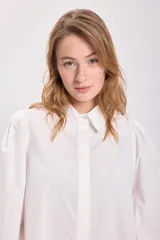 Camisa blanca de mangas largas con hombreras y cuello clásico.