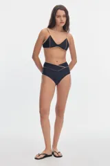 Top de bikini negro con escote en V, tirantes finos y detalles de vivos en tono tostado a contratono.
