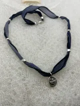 Collar con cinta de raso azul y cuentas plateadas, con dije ovalado plateado con la imagen del Espíritu Santo.