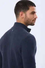 Cardigan de punto grueso color azul marino, con cuello alto, cierre frontal de botones y ribetes en contraste color marrón.