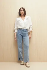 Jean de corte recto confeccionado en denim con spandex, de tiro medio y color azul claro. Presenta un tajo lateral en el ruedo de ambas piernas.