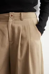 Pantalón pinzado de corte ancho, color beige, con bolsillos laterales y botamanga con vuelta.