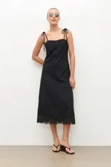 Vestido midi negro con tirantes ajustables mediante lazos, escote recto y detalle de encaje bordado en el pecho y en el ruedo.