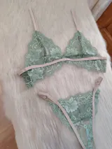 Conjunto de lencería compuesto por un bralette triangular y una bombacha tipo tanga, confeccionados en encaje color verde oliva con detalles y elásticos en tono tostado.