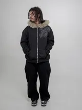 Campera de algodón y poliéster color negro con cierre frontal y capucha con borde de piel sintética. Cuenta con bolsillos frontales estilo canguro y diseño estampado en el pecho.