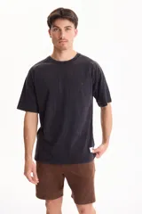 Remera oversize de manga corta raglán, color negro con efecto lavado acid wash, corte semi boxy y detalle de etiqueta lateral en el ruedo.