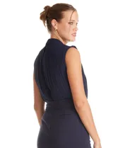 Enterito de crepe color azul marino, con torso plisado sin mangas y cuello alto. Presenta corte en la cintura con lazo de ajuste y pantalón de pierna recta con bolsillos funcionales.