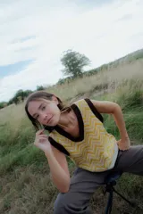 Chaleco de punto sin mangas con escote en V, presenta un diseño estampado geométrico en tonos amarillo y blanco con terminaciones en color marrón oscuro.