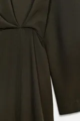 Vestido midi de Zara Woman Collection, color verde oscuro, con cuello redondo, manga larga y detalle de pliegues en el delantero. Presenta un corte recto con abertura frontal en el bajo y cierre lateral con cremallera oculta.