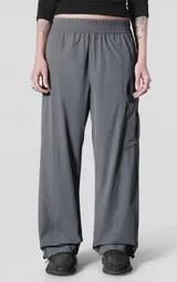 Pantalón de corte oversize confeccionado en microfibra técnica elastizada, color gris carbón. Presenta cintura elástica, bolsillos laterales, un bolsillo cargo con cierre de broche snap y sistema de elásticos con tancas en los tobillos para regular la apertura.