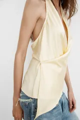 Top de tejido satinado con cuello halter y escote en pico cruzado. Presenta un diseño de espalda descubierta y bajo asimétrico con cierre lateral.