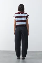 Jean de corte barrel con silueta curva y volumen controlado, de tiro medio y color negro. Presenta un diseño que se ensancha en la pierna y se ajusta levemente en el bajo, con cierre frontal y bolsillos laterales.