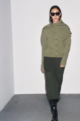 Chaqueta de tejido de punto color verde musgo, de corte cropped, con cuello redondo y cierre frontal de botones oscuros.