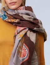 Pashmina rectangular con estampado multicolor en tonos tierra, naranja, verde y amarillo. Presenta motivos geométricos y florales en secciones definidas.