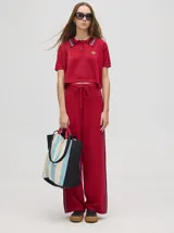 Pantalón de punto rojo de tiro alto, corte holgado y pierna ancha, con pretina elástica con cordón de ajuste y franjas laterales en color celeste y negro.