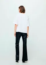 Pantalón de tiro medio efecto piel color negro, de corte flare, con adorno de tachuelas plateadas a lo largo de las costuras laterales.