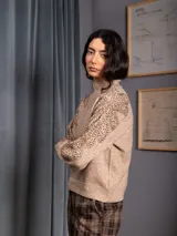 Buzo de cuello alto color gris, de manga larga, con detalle de bordado floral con lentejuelas en el hombro y parte superior de la manga.