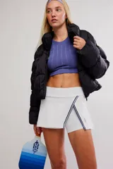 Skort deportivo blanco de tiro alto, con diseño cruzado en el frente y ribetes en contraste azul oscuro, que incluye short interno incorporado.