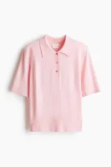 Remera polo de punto fino color rosado, con cuello, tapeta de tres botones, mangas al codo y terminaciones acanaladas en mangas y bajo.