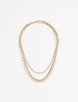 Collar de tres cadenas superpuestas, todas en tono dorado. La cadena más corta es de eslabones pequeños, la del medio es de eslabones tipo serpiente y la más larga es de eslabones ovalados grandes.