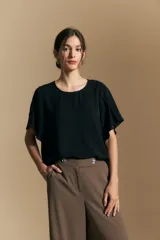 Top de color azul, con escote redondo a la base y mangas cortas amplias con caída fluida. Presenta una silueta relajada y un diseño minimalista.