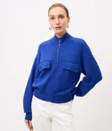 Campera de punto pesado color azul, con cuello alto, cierre frontal con cremallera y bolsillos delanteros con solapa y botones. Cuenta con mangas largas y puños y bajo acanalados.