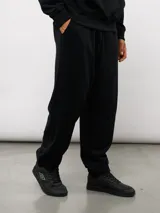 Pantalón jogger de felpa sin frisa, color gris claro melange, con logo bordado de Umbro en azul oscuro en el muslo izquierdo y puños elásticos en los tobillos.