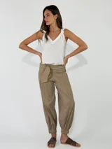 Pantalón beige con textura arrugada, de corte holgado estilo balloon con puños elásticos en los tobillos y cintura alta con faja y lazo ajustable.
