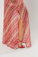 Vestido midi de crochet con diseño de ondas en tonos rojo, rosa y beige. Tiene un solo hombro y tajos laterales.