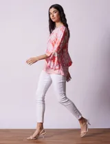 Blusa color salmón con estampado floral blanco, cuello redondo con abertura y mangas 3/4 acampanadas.
