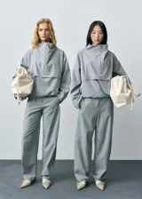 Anorak de diseño oversize en color gris, con cuello chimenea y cierre frontal de cremallera. Presenta mangas largas y ruedo elástico, confeccionado en tejido con acabado estructurado.