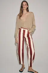 Jeans de tiro alto con corte barrel y diseño de rayas verticales en color bordó y beige. Presenta cierre frontal con cremallera y botón, trabillas en la cintura y bolsillos funcionales en delantero y espalda.