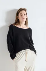 Sweater de punto de corte amplio y holgado, con cuello barco y mangas largas. Presenta una textura esponjosa y un diseño minimalista.