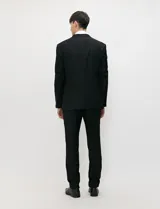 Traje de tres piezas color negro, compuesto por saco de dos botones, chaleco entallado y pantalón de corte slim, confeccionado en tejido de fantasía con spandex.
