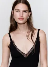 Vestido midi negro confeccionado en tejido de punto acanalado, con tirantes finos, escote en V y detalles de encaje en el escote y en el bajo asimétrico.