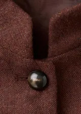 Chaqueta de mezcla de lana color marrón, de corte recto, con cuello mao, cuatro bolsillos con solapa en el frente y cierre de botonadura central.