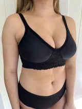 Corpiño reductor negro de lycra suave con compresión ligera y refuerzo en la parte de la copa. Tiene detalle de encaje en la parte delantera, escote alto y laterales anchos para mayor contención. La copa es profunda y tiene broches en la espalda con tres ajustes.