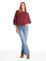 Capa de punto color bordó con diseño envolvente de doble capa superpuesta. Presenta cuello a la base, cierre frontal con botones y mangas estilo japonés con terminaciones acanaladas.