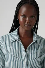 Camisa de denim a rayas verticales verdes y blancas, con cuello clásico, manga corta y cierre frontal con botones.