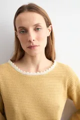 Sweater de punto negro con escote bote, mangas largas y detalles de terminación en ondas de color blanco en el cuello, los puños y el ruedo.