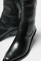 Bota de caña media estilo western, confeccionada en cuero negro, con taco cuadrado y punta cuadrada.