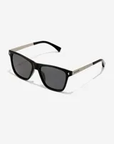 Lentes de sol unisex con marco cuadrado negro, patillas metálicas plateadas y cristales polarizados oscuros.