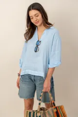 Blusa celeste de lino, con cuello en V, mangas largas con vuelta y diseño holgado.