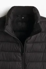 Campera puffer liviana de corte ajustado, con cuello elevado y cierre frontal. Presenta diseño acolchado horizontal, bolsillos laterales ocultos y acabado repelente al agua.
