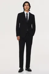 Camisa blanca de manga larga con cuello inglés, tapeta lisa y bajo redondeado. Presenta canesú en la espalda y puños ajustables con botón.