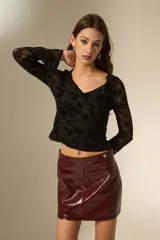 Top de manga larga con cuello en V, confeccionado en tela de tul con estampado floral aterciopelado en color negro.