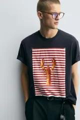 Camiseta azul marino de corte relaxed fit, cuello redondo y manga corta. Presenta un parche rectangular estampado con rayas horizontales rojas y blancas, y un dibujo de una langosta en el centro.