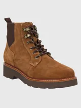 Bota de gamuza color tostado con cordones frontales y paneles elásticos laterales. Presenta una suela de goma gruesa con costuras decorativas, ojales metálicos y tirador trasero para facilitar el calce.