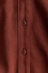 Camisa de mezcla de lino y viscosa color terracota, con cuello abierto, escote en V con botonadura frontal, hombros caídos y mangas tres cuartos holgadas.